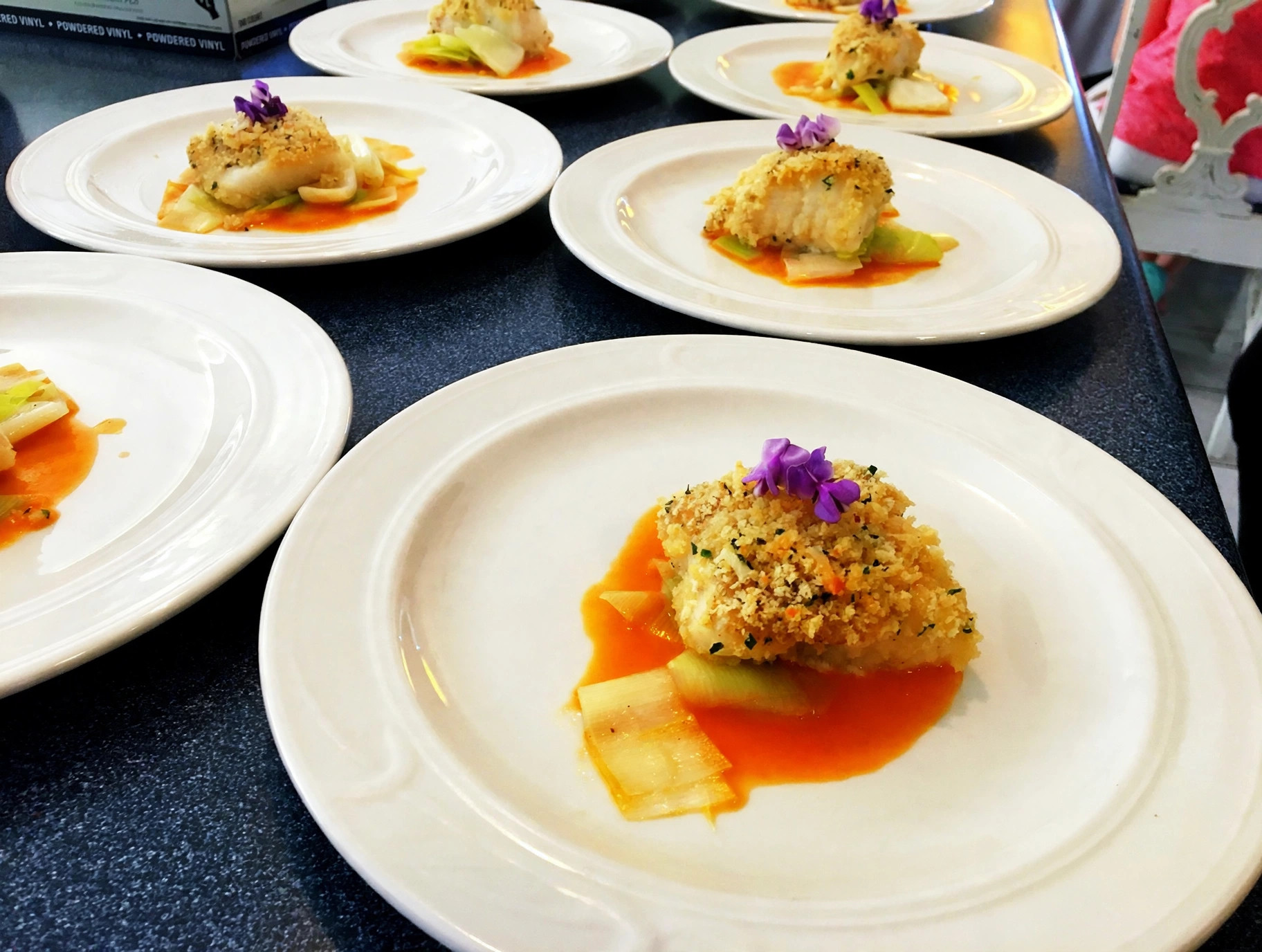 Herb-crusted fish with edible flowers and citrus sauce