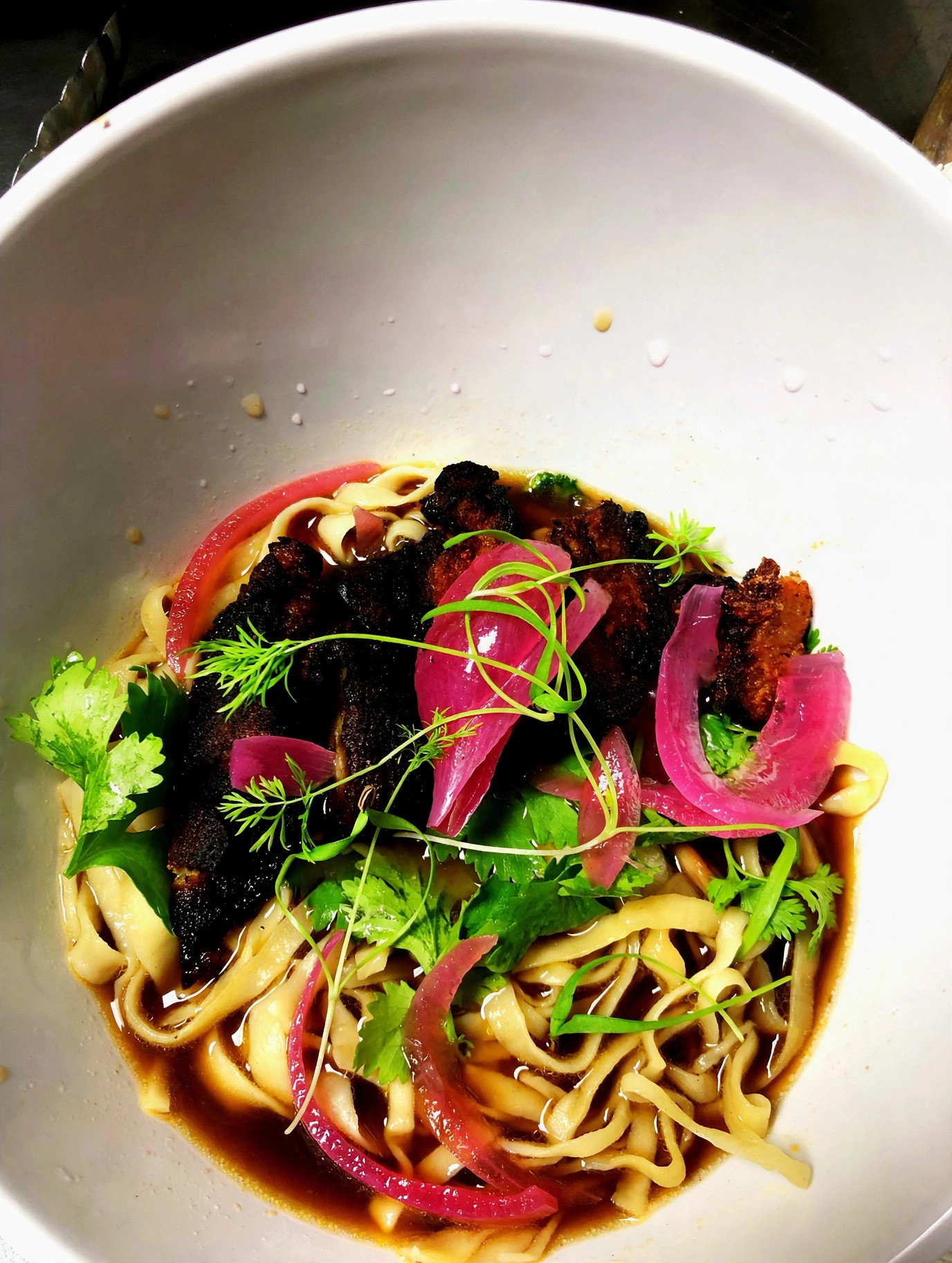 Crispy pork belly noodle bowl with pickled onions