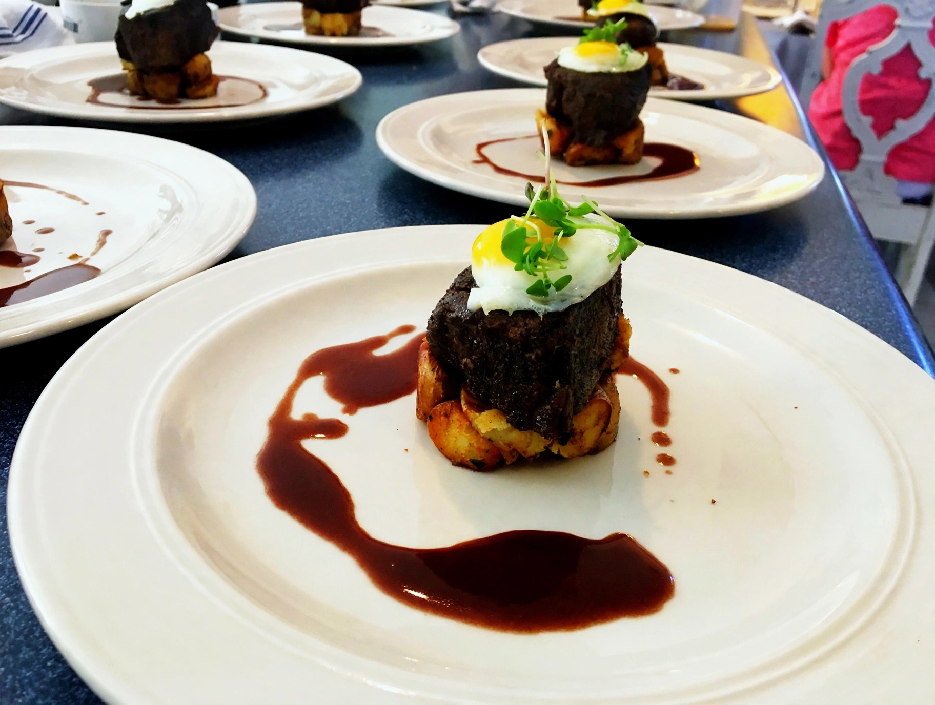 Beef tenderloin with fried egg and microgreens over potatoes